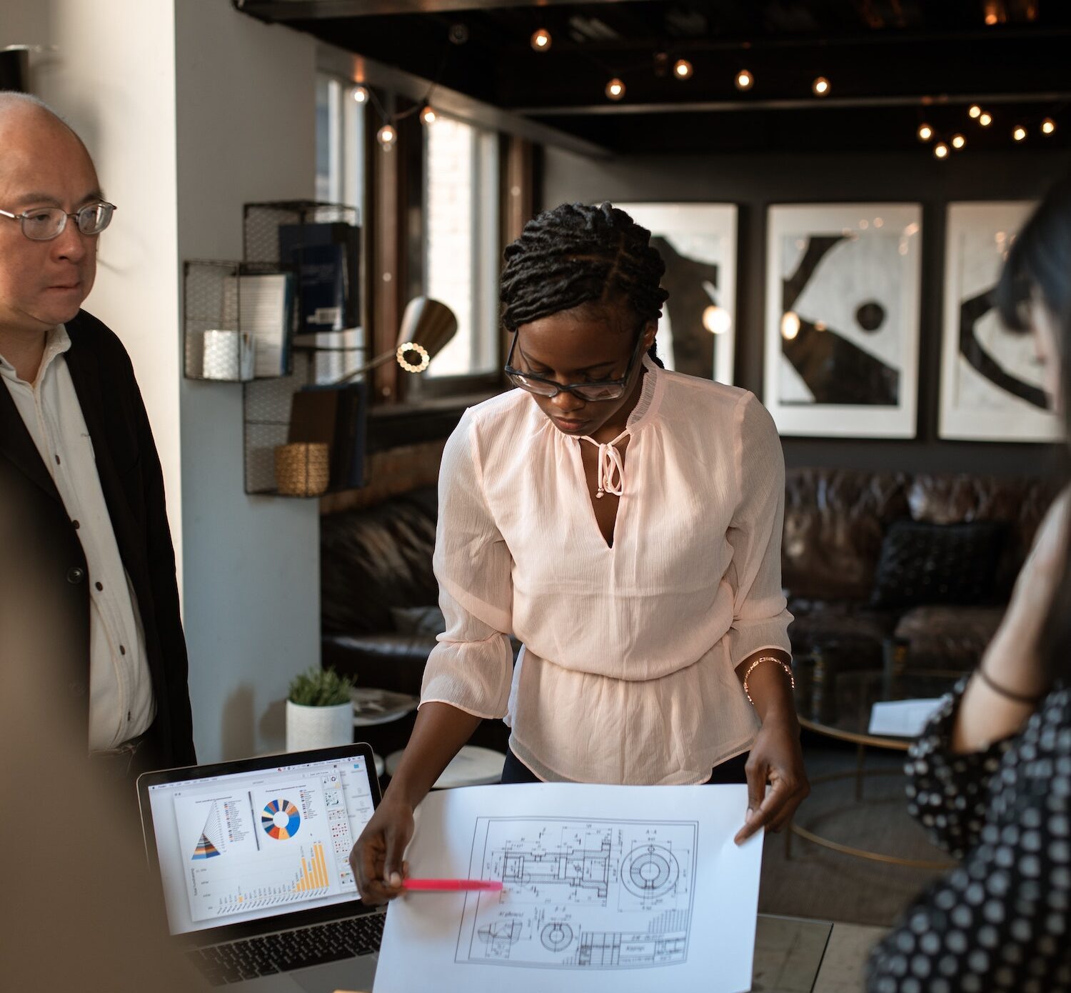 A person presenting an engineering drawing to two other people