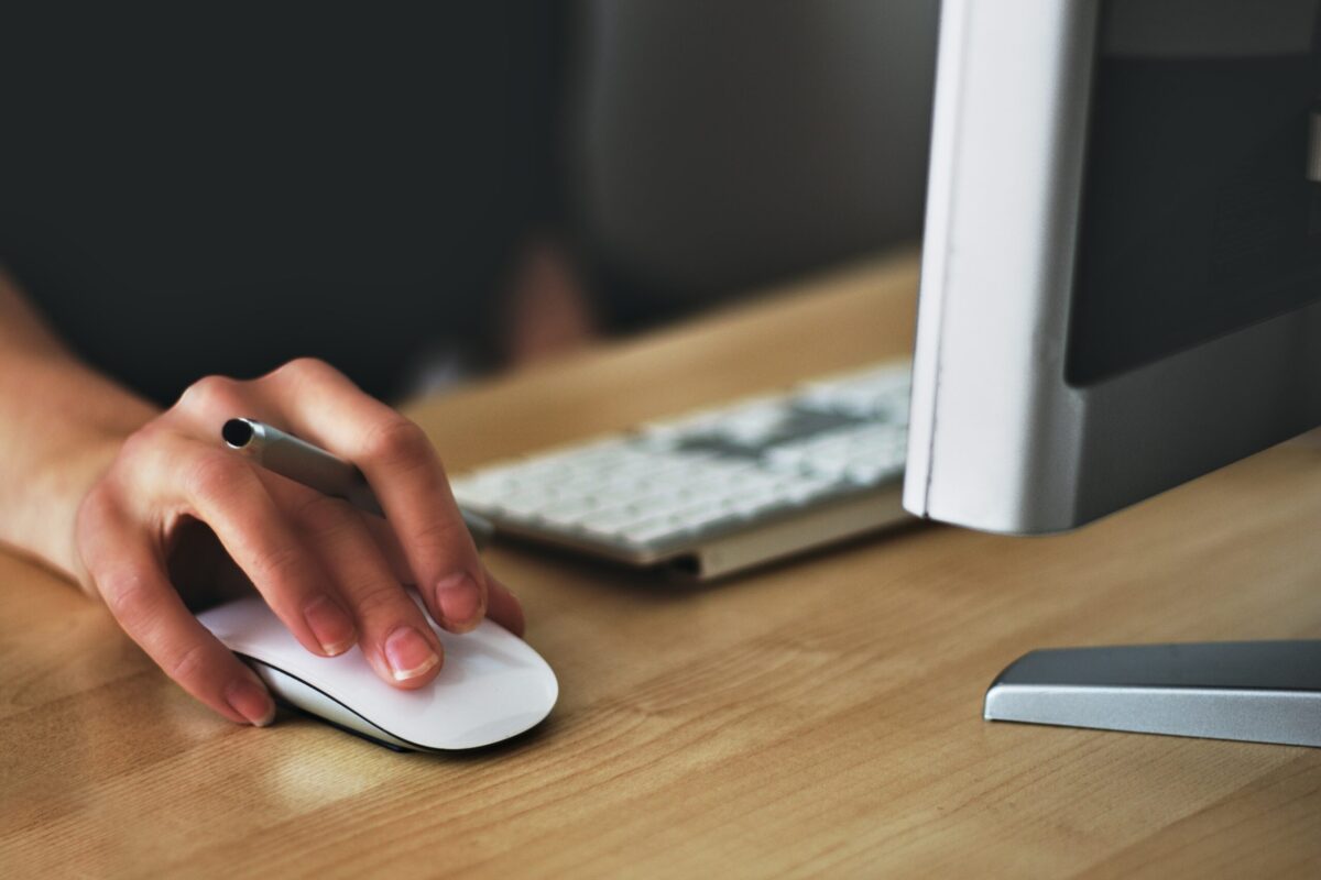 person at a computer desk with their hand on the mouse