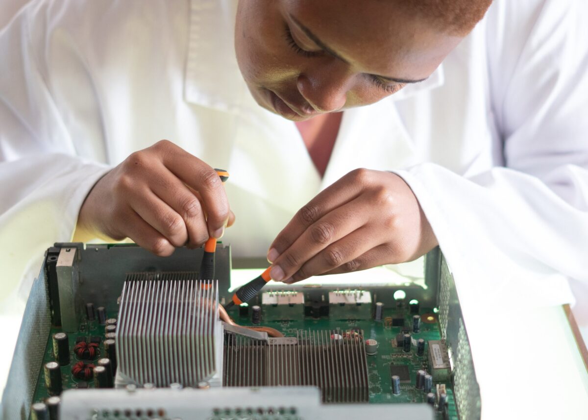 a woman working on a computer board wearing a white lab coat